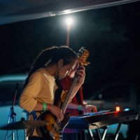 mid adult man playing a bass guitar in a band at an outdoor music festival - concert stock pictures, royalty-free photos & images