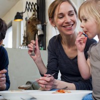 mid adult parents and two daughters eating a spaghetti meal - food stock pictures, royalty-free photos & images