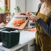 mid adult woman putting carrot shavings in compost bin - food stock pictures, royalty-free photos & images