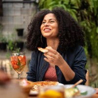 mid adult woman talking and eating with friends at restaurant - food stockfoto's en -beelden