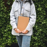 midsection of a mid adult woman with brochure in hands against a green plants outdoors. - garden decoration stock pictures, royalty-free photos & images