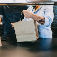 midsection of chefs working together while holding paper bags at restaurant kitchen counter - junk food stock pictures, royalty-free photos & images