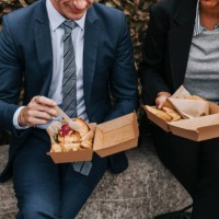 midsection of male and female business professionals having lunch while sitting on bench - junk food stock pictures, royalty-free photos & images