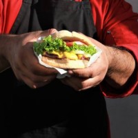 midsection of man holding burger against wall,mexicali,mexico - junk food stock pictures, royalty-free photos & images