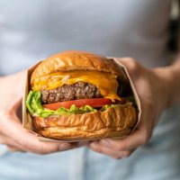 midsection of woman holding burger - junk food stock pictures, royalty-free photos & images