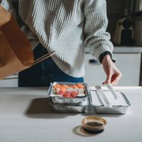 millennial woman is unpacking sushi takeaway food delivery at home - junk food stock pictures, royalty-free photos & images