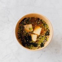 miso traditional japanese soup with tofu, mushrooms, spring onion and sesame seed mix in cardboard reusable glass. high angle view. - junk food stock pictures, royalty-free photos & images