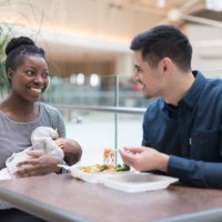 mixed race couple eating lunch with their newborn at the mall - junk food stock pictures, royalty-free photos & images