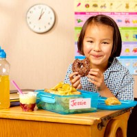 mixed race school girl eating donut - junk food stock pictures, royalty-free photos & images