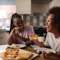 mixed race woman laughing at joke near friend - junk food stock pictures, royalty-free photos & images