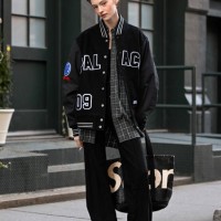 Model Aine O'Leary is seen wearing a varsity jacket, plaid shirt, black pants, black boots and black and white bag outside the Ashlyn show during...