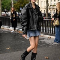 Model is seen wearing a black biker jacket, denim skirt and black boots outside the Chanel show during the Womenswear Spring/Summer 2024 as part of...