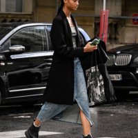 Model is seen wearing a black coat, white top, blue denim slit skirt and black boots outside the Giambattista Valli show during Womenswear...