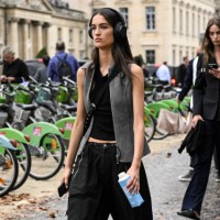 Model is seen wearing a black shirt, gray vest and black cargo pants outside the Chanel show during the Womenswear Spring/Summer 2024 as part of...