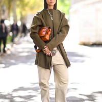 Model is seen wearing a green coat, green sweater, tan pants and brown bag outside the Miu Miu show during Womenswear Spring/Summer 2025 as part of...