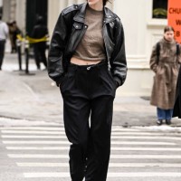 Model Jace Higgins is seen wearing a black leather jacket, tan sweater, black pants and black studded shoes and black bag outside the Kallmeyer show...