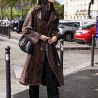 Model Jade Nguyen is seen wearing a brown leather trench coat and black and gold chain bag outside the Chanel show during the Womenswear...
