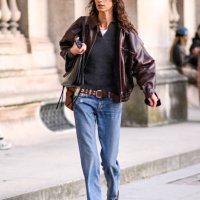 Model Mica Arganaraz is seen wearing a brown leather jacket, black sweater, blue jeans, brown belt and black bag outside the Louis Vuitton show...