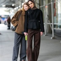 Model wears a brown oversized jacket, a turtleneck, gray pants, brown loafers ; a model wears a brown balaclava / hood, a black belted jacket, brown...