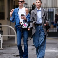 Model wears a white sleeveless crop top paired with a blue denim jacket. The jacket features a classic collar and button-down front. Blue denim jeans...