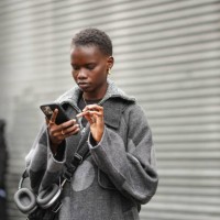 Model wears gold earrings, gold necklace, dark gray light gray polka dotted wool coat, outside Brandon Maxwell, during the New York Fashion week...