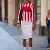 Model wears sunglasses, a red and white striped polo shirt, a white on-knee skirt, white socks, Adidas blue and yellow striped sneakers shoes,...