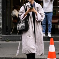 Model Xu Wei is seen wearing a tan trench coat, black bag and black Miu Miu sunglasses outside the Lacoste show during Womenswear Spring/Summer 2025...