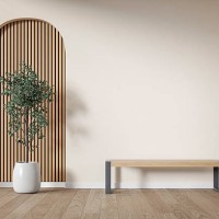 modern interior: an unfurnished living/waiting room with a modern bench, a potted plant (ficus) in front of a partly textured light beige (cream) neutral wall, partly arched paneled light pink wooden slat, large window and de