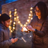 mom & daughter untangling the string lights together while they are decorating the garden at dusk - garden decoration stock pictures, royalty-free photos & images