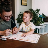 mom painting smiling son's finger nails at kitchen table - nails art photos et images de collection