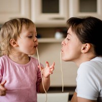 mother and child eating spaghetti together - food stockfoto's en -beelden
