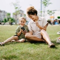 mother and daughter are sitting on the grass in the park - fashion stock pictures, royalty-free photos & images