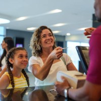 mother and daughter cheerfully buying movie tickets at movie theater box office - junk food stock pictures, royalty-free photos & images