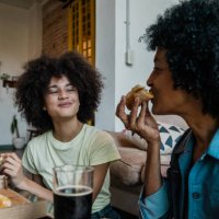 mother and daughter eating pizza in the living room at home - junk food stock pictures, royalty-free photos & images