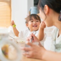 mother and her small daughter enjoying eating salad and drinking smoothie at home - food stock pictures, royalty-free photos & images