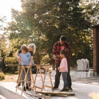 mother and son using hand saw while father talking to daughter outside house - garden decoration photos et images de collection