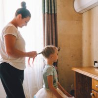 mother braids her little daughter in front of the mirror in bright living room. family weekend. profile view - hairstyle stock pictures, royalty-free photos & images