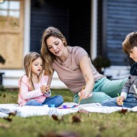 mother helping children paint in front yard of rural farmhouse - garden decoration photos et images de collection