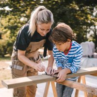 mother measuring wooden plank by son at construction site - home decoration stock pictures, royalty-free photos & images