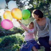 mother with daughter (6-7) holding balloons sitting in garden - garden decoration stock pictures, royalty-free photos & images