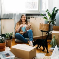 moving day: happy plus size woman sitting on the floor among boxes having a lunch break - junk food stock pictures, royalty-free photos & images