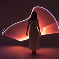 mujer joven frente a senderos de luz naranja. - fashion fotografías e imágenes de stock