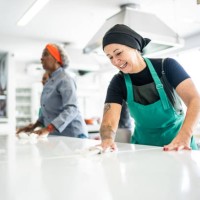 mujer madura limpiando el mostrador de la cocina en la cocina comercial - food fotografías e imágenes de stock