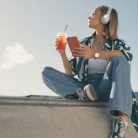 mujer, smartphone en la ciudad y bebida, escuchando música y mirando la vista del paisaje urbano, streaming y verano. joven mujer relájese en un parque urbano, lista de reproducción de audio y radio con té helado y gen z - fa