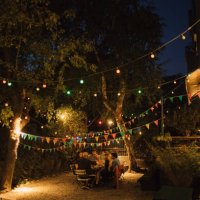 multi-ethnic friends enjoying dinner party in illuminated backyard - garden decoration stock pictures, royalty-free photos & images