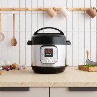 multi cooker on kitchen counter with onions, garlic, cooking oil and cutting board - food stockfoto's en -beelden