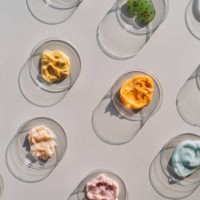 multicolored creams and scrubs in many petri dishes on gray background. concept of cosmetics laboratory researches. photography in flat lay style - food stock pictures, royalty-free photos & images