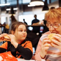multigenerational family enjoying dinner at fast food restaurant - junk food stock pictures, royalty-free photos & images