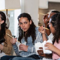 multiracial family watching tv, eating take out food - junk food stock pictures, royalty-free photos & images