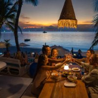 multiracial friends at the dinner at the beach restaurant toasting with wine - travel stock pictures, royalty-free photos & images